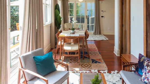 A spacious room with a dining area, a sofa, and a small table. - Cosy 3 Bedroom Villa in Freeman's Bay (Auckland)