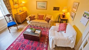 Un salon chaleureux avec un canapé, un fauteuil, une petite table et un tapis à motifs.