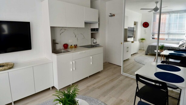 Eine moderne Küche mit weißen Schränken, einer Marmor-Spritzschutzleiste und einem Essbereich mit Tisch und Stühlen.