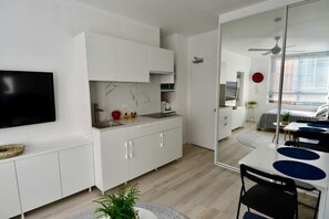 A modern kitchen with white cabinets, a marble backsplash, and a dining area with a table and chairs. - Cute Studio Apartment in Maroubra (Maroubra)