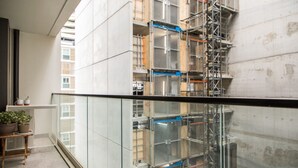 Un edificio de gran altura en construcción, con andamios y elementos estructurales expuestos.