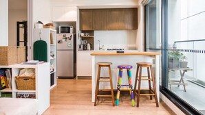 Una cocina moderna con armarios de madera, una isla central con taburetes y vista a la calle a través de un ventanal grande.