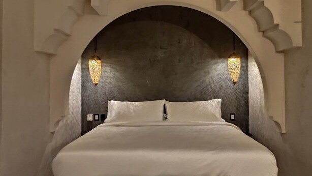 Ein Schlafzimmer mit einem großen Bett, einer gewölbten Decke und zwei Hängeleuchten.