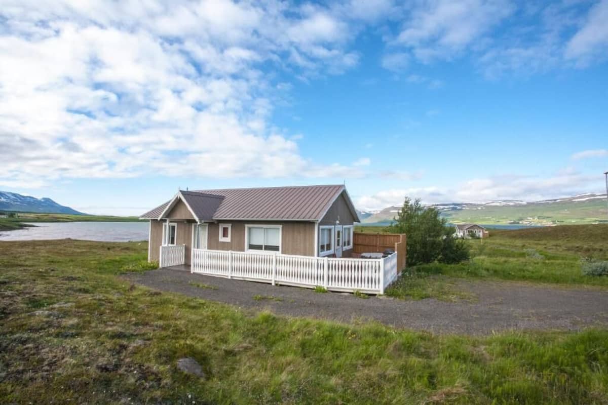 Une maison de plain-pied avec un toit en pente, une clôture blanche en bois et une allée gravillonnée.