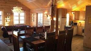 A wooden cabin interior with a dining area, a sofa, and a kitchen. - Vacation Home Fagravik (Akureyri)