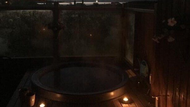 A rooftop terrace with a hot tub and a lantern, overlooking a sunset and distant mountains. - Vacation Home Fagravik (Akureyri)