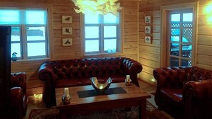 A cozy wooden cabin interior with a leather sofa, a wooden coffee table, and a chandelier. - Vacation Home Fagravik (Akureyri)