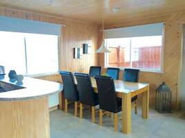A wooden interior with a dining table and chairs, a hanging light fixture, and a lantern.
