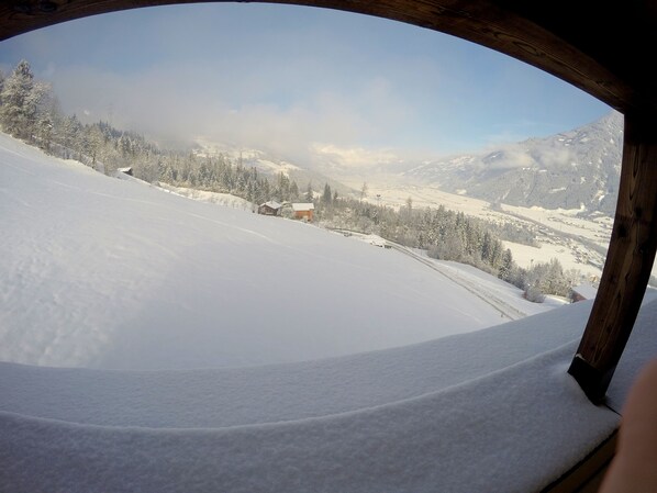 A panoramic view of a snow-covered landscape with a wooden structure framing the scene.