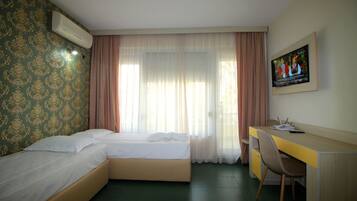 Una habitación de hotel con una cama, un escritorio y un televisor en la pared.