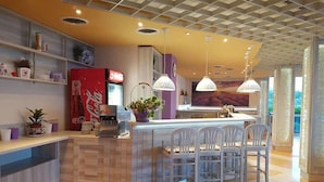 Une cuisine moderne dotée d’un îlot central, de chaises blanches, de luminaires suspendus et d’un réfrigérateur.