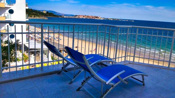 Un balcon avec deux chaises longues donnant sur une plage et la mer.