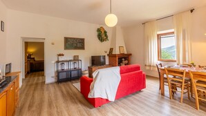 Una sala de estar acogedora con un sofá rojo, una mesa de comedor de madera y una chimenea.