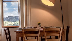 Una mesa de comedor con sillas, un florero con flores y una lámpara.