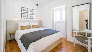 Une chambre à coucher avec un grand lit, une table de chevet, une chaise et un miroir.