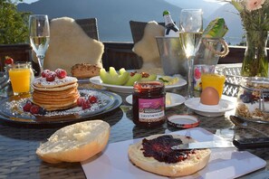 Frühstückstisch mit Pfannkuchen, Beeren und einer Champagnerflasche mit schöner Aussicht.