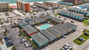 Un hotel con piscina, múltiples estacionamientos y vista al mar.