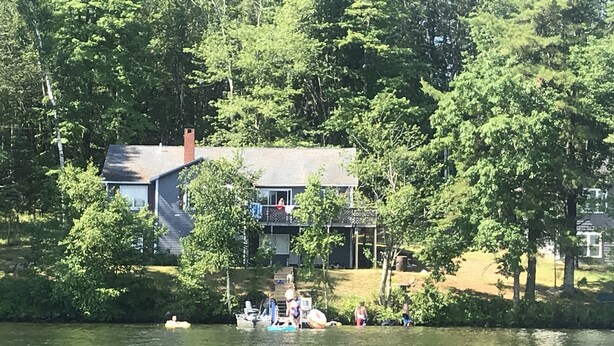 A house with a dock extending into a lake, surrounded by trees. - Waterfront House on Winnipesaukee w Private Dock , Sleeps 11 & Dogs Welcome! (Moultonborough)