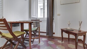 A room with a wooden table, a chair, a small table with a candle and incense sticks, and a window with a curtain. - Charming Colosseum (Rome)