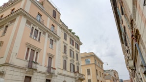 A narrow street lined with historic buildings, featuring balconies and arched windows. - Charming Colosseum (Rome)