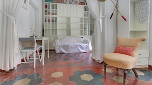 A room with a white desk, a covered bed, a chair, a bookshelf, and a patterned floor. - Charming Colosseum (Rome)