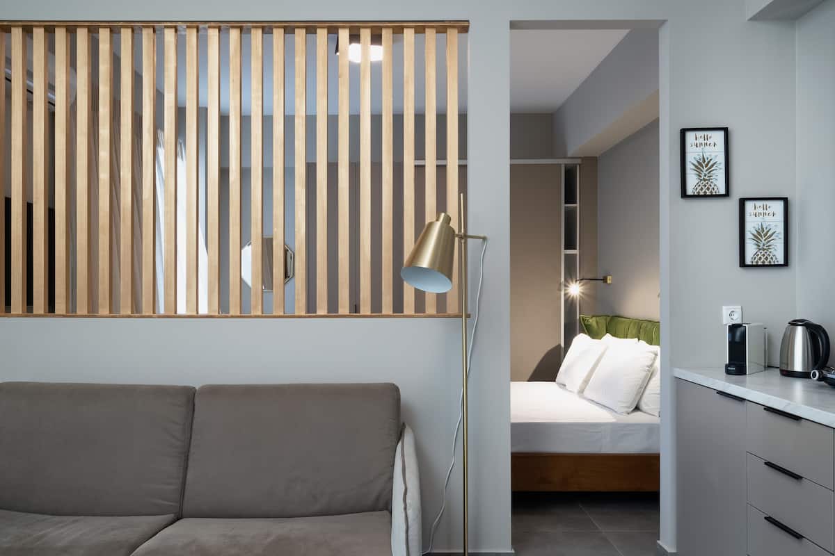 Une chambre moderne comprenant un canapé, un lit, une cloison en bois et un coin cuisine.