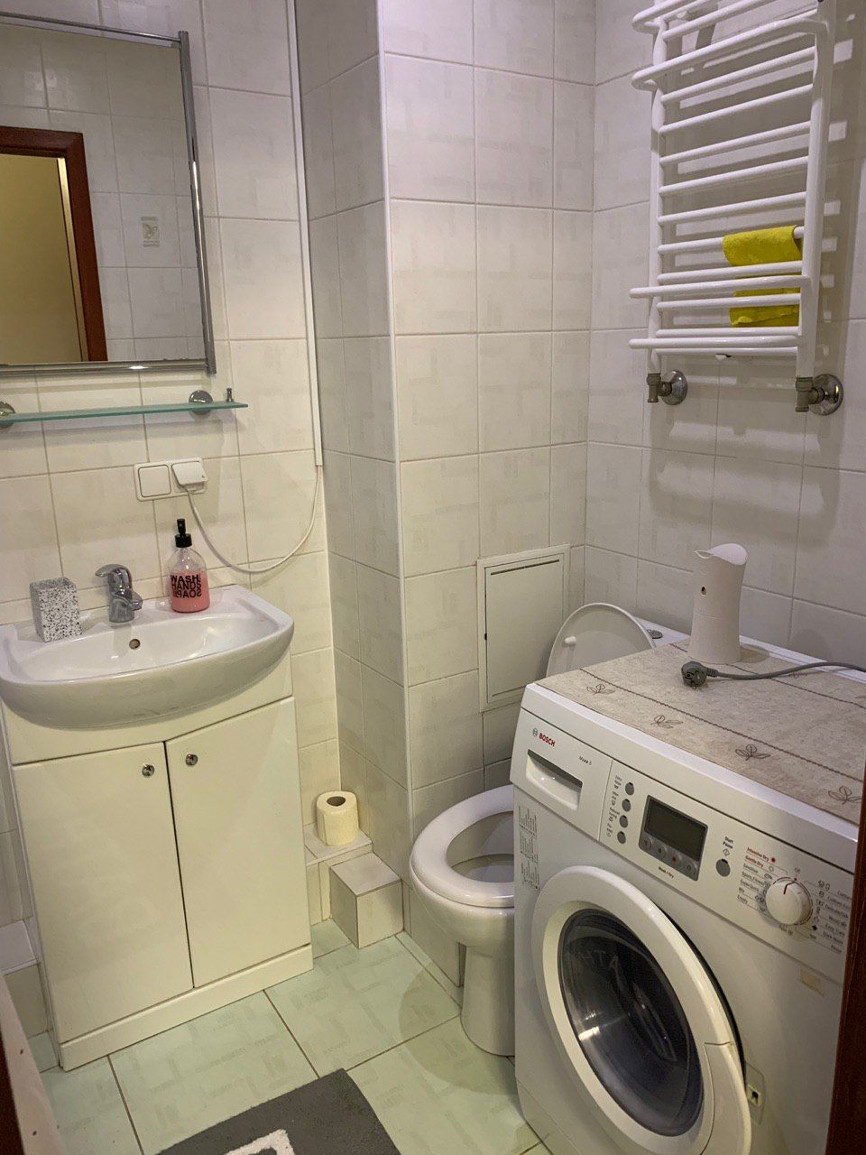A compact bathroom with a sink, toilet, and washing machine.