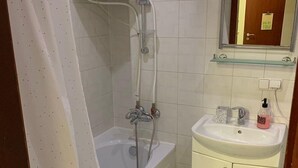 Een badkamer met een bad, wastafel, spiegel en douche.