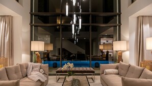 Un salon moderne avec deux canapés, une table basse et une grande fenêtre donnant sur une piscine et un escalier.