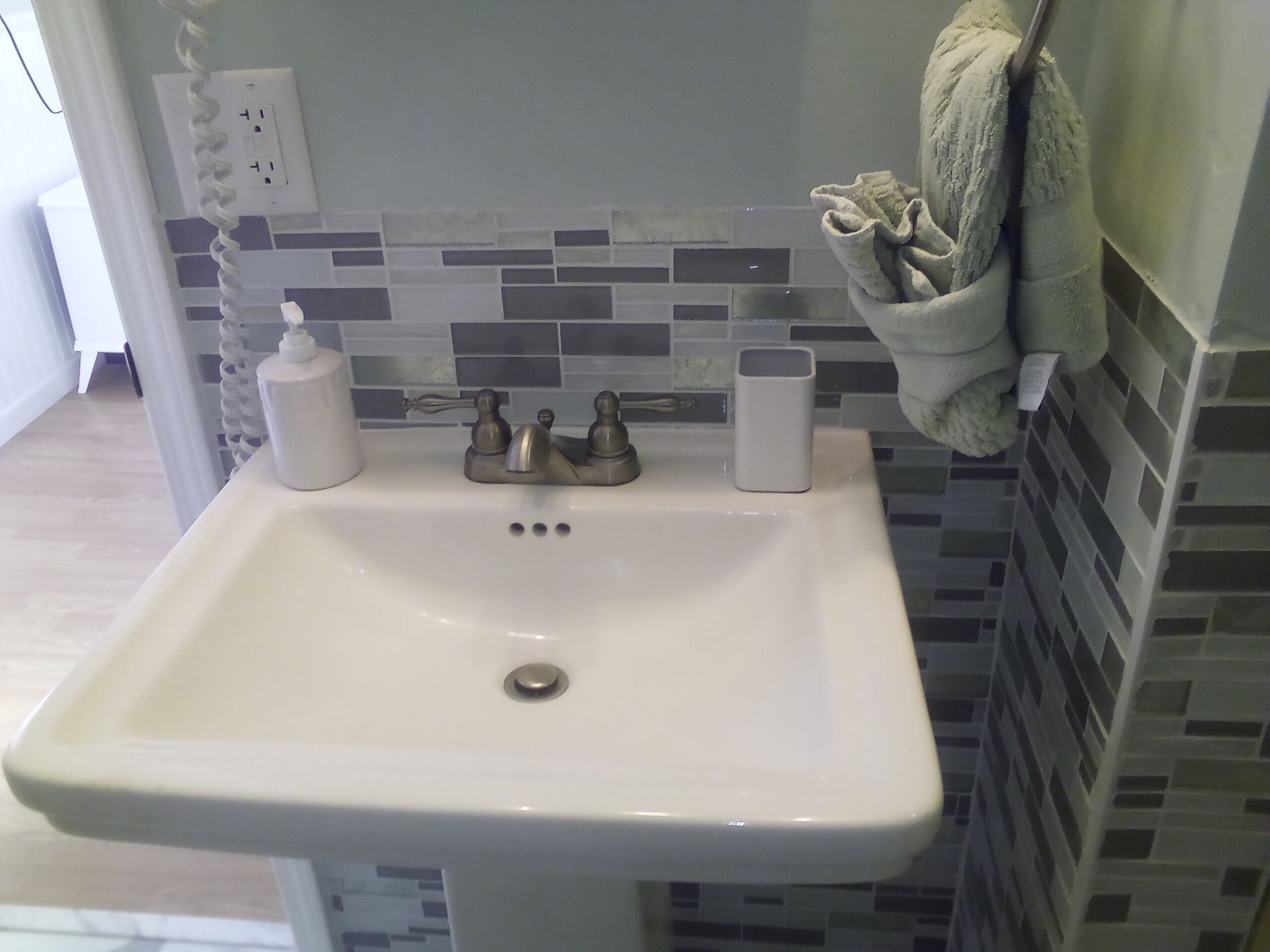 A bathroom with a white sink, a towel rack, and a tiled backsplash.