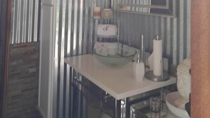 A bathroom with a white sink, a mirror, a chandelier, and striped wallpaper. - Private Suite (Paso Robles)