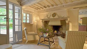 A cozy room with a fireplace, a table with flowers, and two chairs. - Wonderful  villa for 5 people with pool, WIFI, TV and patio (Vivo D'orcia)