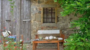 A rustic outdoor seating area with a wooden bench, a table with a basket, and a stone wall with a window. - Wonderful  villa for 5 people with pool, WIFI, TV and patio (Vivo D'orcia)