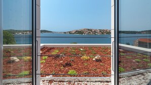 A balcony with a view of a lake and a town across the water. - Luxury Villa Carpe Diem Paradise (Rogoznica)