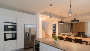 A modern kitchen with built-in appliances, a central island, and pendant lighting. - Luxury Villa Carpe Diem Paradise (Rogoznica)