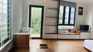 A modern, well-lit room with a kitchen area, a dining table, a bed, and a TV. - Rang Dong hotel (Hue)