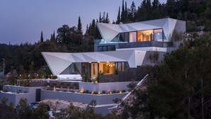 Une maison moderne au design géométrique original, dotée de grandes fenêtres et d’un intérieur bien éclairé.