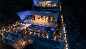 Une maison moderne à plusieurs niveaux, dotée d’une piscine, d’un espace extérieur aménagé et d’un intérieur bien éclairé.