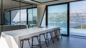 Une cuisine moderne dotée d’un grand îlot central, de tabourets de bar et offrant une vue sur un lac et des montagnes.