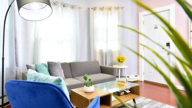 A modern living room with a grey sofa, a blue armchair, a glass coffee table, and a floor lamp. - Cozy apartment 3rd 10min Walk Downtown | City View (Providence)