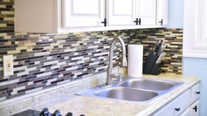 A kitchen with a double sink, white cabinets, and a mosaic tile backsplash. - Cozy apartment 3rd 10min Walk Downtown | City View (Providence)