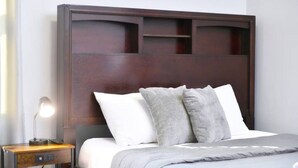 A hotel room with a large wooden headboard, a bed with white and grey bedding, and a bedside table with a lamp. - Cozy apartment 3rd 10min Walk Downtown | City View (Providence)