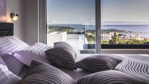 Un dormitorio con un amplio ventanal que ofrece vistas a la ciudad y al mar.