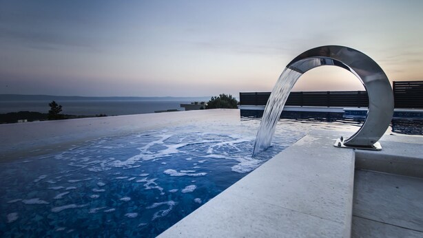 Un jacuzzi con cascada, con vistas a un cuerpo de agua y un horizonte lejano.