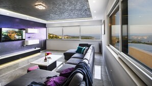 Una sala de estar moderna con un televisor grande, un sofá, una mesa de centro y vistas de la ciudad.
