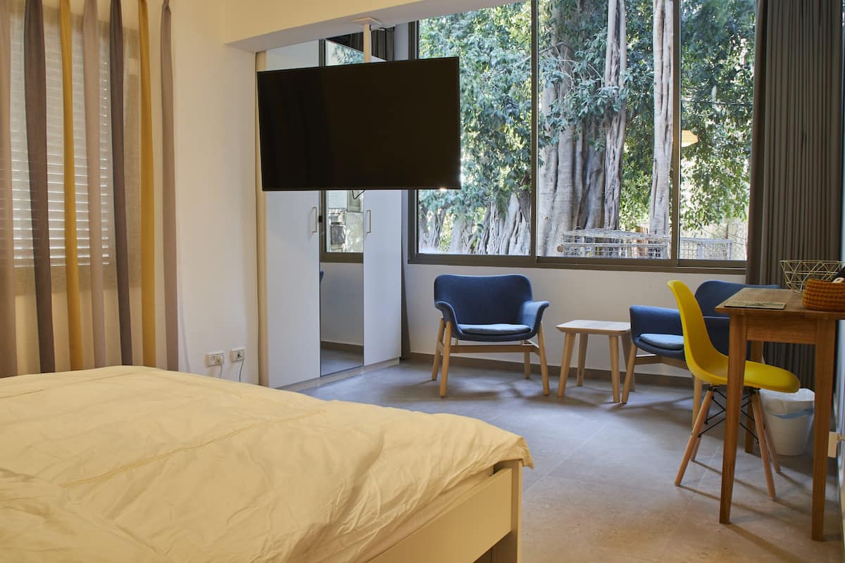 A hotel room with a bed, a TV, a small table, and two chairs.