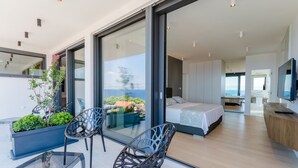 A modern bedroom with a large bed, a TV, and a balcony with chairs and a table. - Luxury Villa Soleil with Swimming Pool (Sutivan)