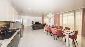 A modern kitchen with a built-in stove, a dining area with a table set for four, and a living area with a sofa and TV. - Beachfront Villa Baronessa with Pool (Kastela)