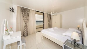 A hotel room with a bed, a desk, a chair, a vanity with a mirror, and a view of the sea. - Beachfront Villa Baronessa with Pool (Kastela)