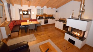 A cozy loft-style living space with a kitchen, dining area, and a fireplace. - Comfort Chalet Mühle - SKI in/SKI out, Sauna-Jacuzzi - by "wachterhof" (Kaltenbach)